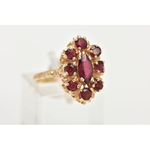 68 - A 14CT GOLD GARNET RING, of an oval form, set with a central marquise cut garnet within a surround o... 