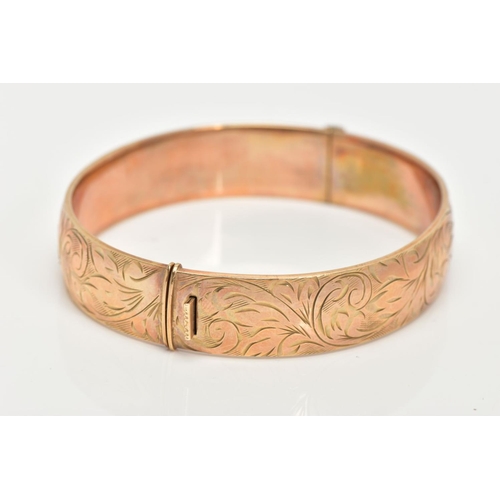 70 - A 9CT GOLD HINGED BANGLE, decorated with a foliate design all round, approximate band width 12.7mm, ... 