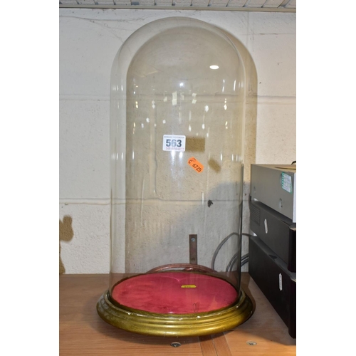 563 - A LATE VICTORIAN GLASS DOME OF CYLINDRICAL FORM, on a circular gold painted wooden base on three fla... 