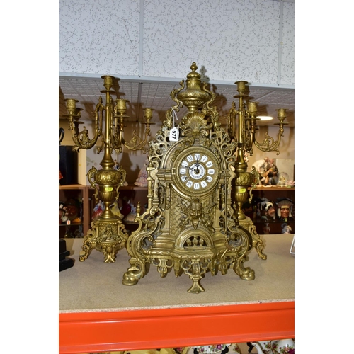 577 - A REPRODUCTION BRASS CLOCK GARNITURE, the clock with ornate cast brass case with twin handled urn su... 