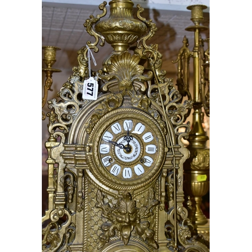 577 - A REPRODUCTION BRASS CLOCK GARNITURE, the clock with ornate cast brass case with twin handled urn su... 