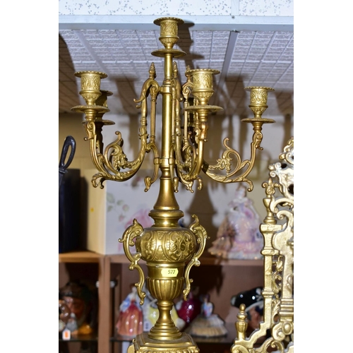 577 - A REPRODUCTION BRASS CLOCK GARNITURE, the clock with ornate cast brass case with twin handled urn su... 