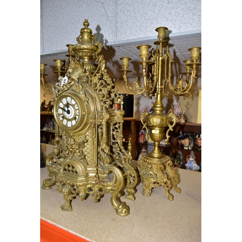 577 - A REPRODUCTION BRASS CLOCK GARNITURE, the clock with ornate cast brass case with twin handled urn su... 