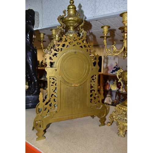 577 - A REPRODUCTION BRASS CLOCK GARNITURE, the clock with ornate cast brass case with twin handled urn su... 