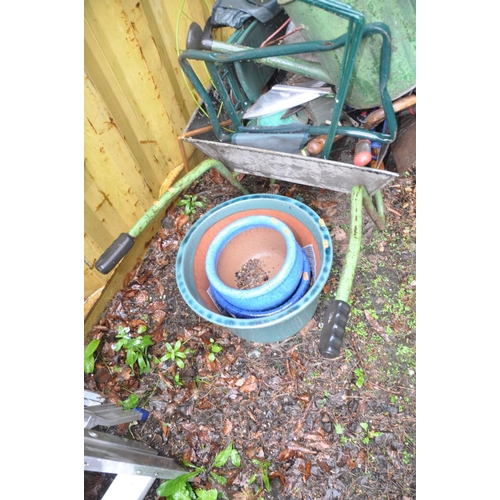 1211 - THREE GLAZED PLANT POTS AND A WHEELBARROW containing a quantity of garden tools