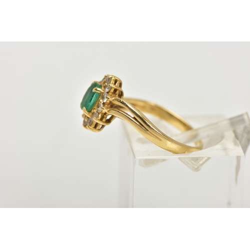 17 - A YELLOW METAL EMERALD AND DIAMOND RING, an oval cut emerald prong set within a surround of twelve r... 