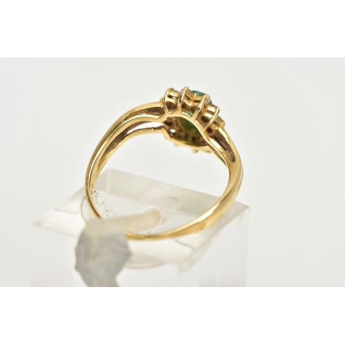 17 - A YELLOW METAL EMERALD AND DIAMOND RING, an oval cut emerald prong set within a surround of twelve r... 