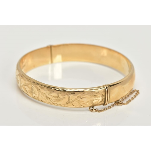 20 - A 9CT GOLD BANGLE, a hollow domed hinged bangle, engraved with a scrolling foliage design, fitted wi... 