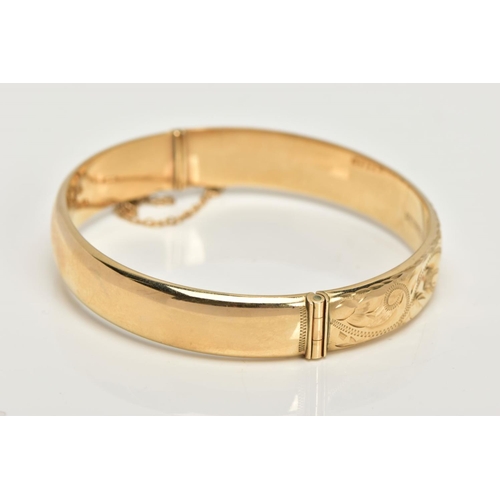 20 - A 9CT GOLD BANGLE, a hollow domed hinged bangle, engraved with a scrolling foliage design, fitted wi... 