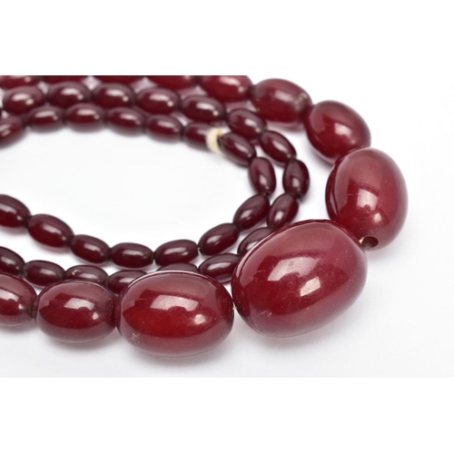 8 - A CHERRY AMBER BAKELITE BEAD NECKLACE, a single row of graduated oval beads, fifty-seven in total, l... 