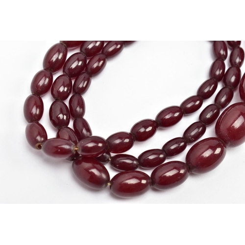 8 - A CHERRY AMBER BAKELITE BEAD NECKLACE, a single row of graduated oval beads, fifty-seven in total, l... 