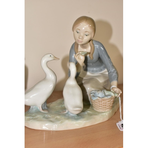 467 - A LLADRO FIGURE AND TWO NAO FIGURES, comprising a Lladro 'Food for Ducks, no.4849, sculpted by Anton... 