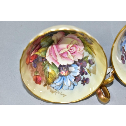 477 - THREE AYNSLEY CABBAGE ROSE TEA CUPS DECORATED BY J.A. BAILEY, comprising pattern no. 1028 with solid... 