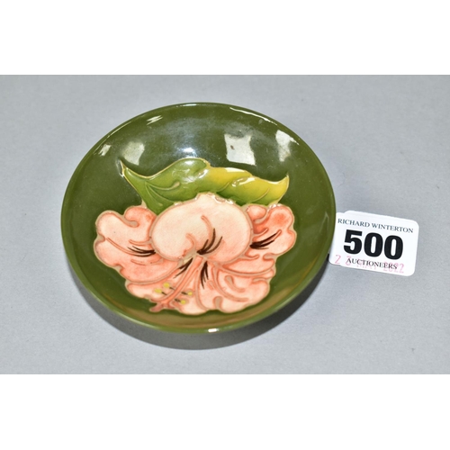 500 - A MOORCROFT POTTERY CIRCULAR PIN DISH DECORATED WITH CORAL HIBISCUS ON A GREEN GROUND, faint impress... 