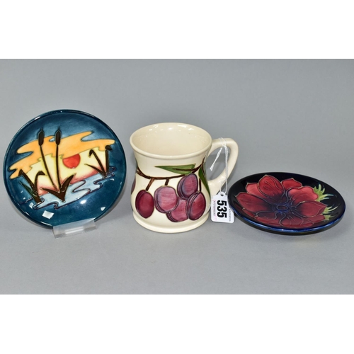 535 - A MOORCROFT POTTERY MUG DECORATED WITH PLUMS ON A CREAM GROUND, height 8.5cm and two circular pin di... 