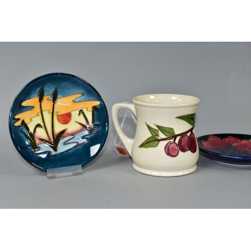 535 - A MOORCROFT POTTERY MUG DECORATED WITH PLUMS ON A CREAM GROUND, height 8.5cm and two circular pin di... 