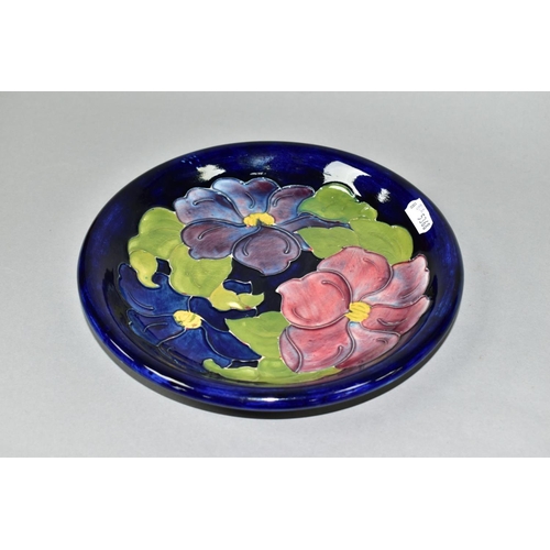 716 - A MOORCROFT POTERY CLEMATIS PATTERN SHALLOW DISH, paper Moorcroft label 'Potters to the Late Queen M... 