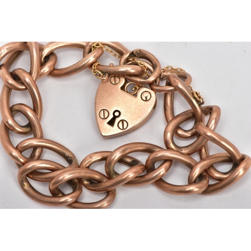 23 - AN EARLY 20TH CENTURY ROSE GOLD CHARM BRACELET, large oval hollow links, fitted with a heart padlock... 