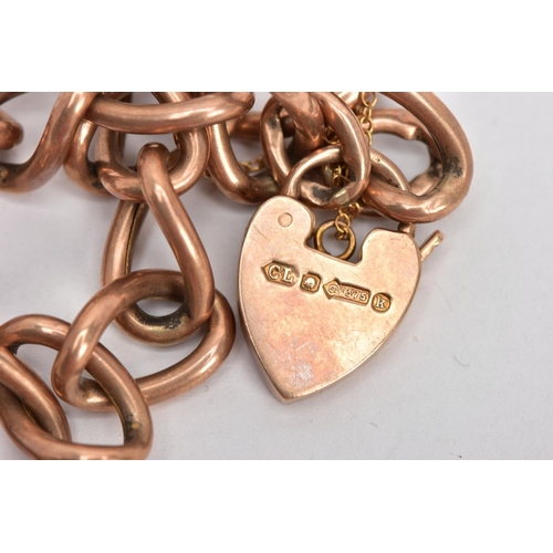 23 - AN EARLY 20TH CENTURY ROSE GOLD CHARM BRACELET, large oval hollow links, fitted with a heart padlock... 