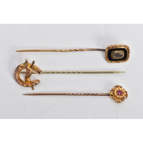 33 - THREE EARLY 20TH CENTURY GOLD STICK PINS, the first a Etruscan style set with circular cut ruby in a... 