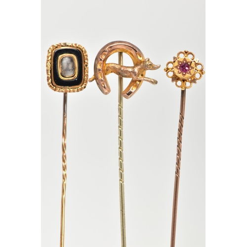 33 - THREE EARLY 20TH CENTURY GOLD STICK PINS, the first a Etruscan style set with circular cut ruby in a... 