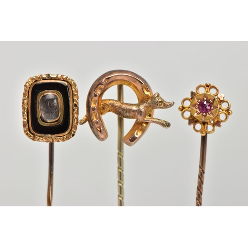 33 - THREE EARLY 20TH CENTURY GOLD STICK PINS, the first a Etruscan style set with circular cut ruby in a... 