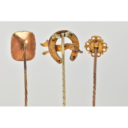 33 - THREE EARLY 20TH CENTURY GOLD STICK PINS, the first a Etruscan style set with circular cut ruby in a... 