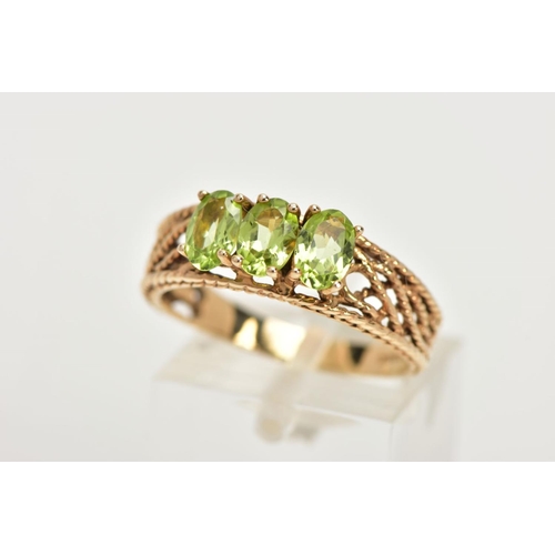 39 - A 9CT GOLD PERIDOT RING, three oval cut peridots prong set in yellow gold, leading on to an open wor... 