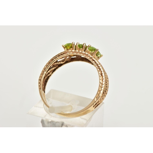 39 - A 9CT GOLD PERIDOT RING, three oval cut peridots prong set in yellow gold, leading on to an open wor... 