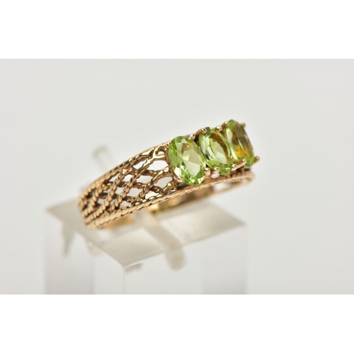 39 - A 9CT GOLD PERIDOT RING, three oval cut peridots prong set in yellow gold, leading on to an open wor... 