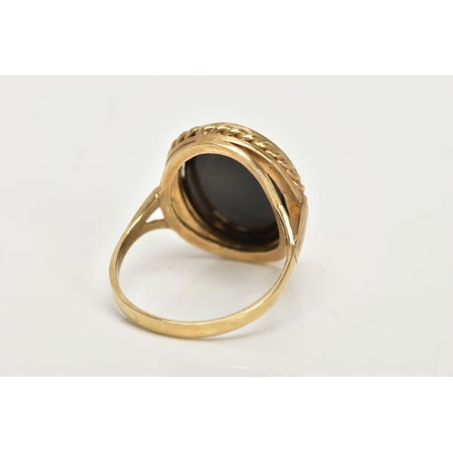 41 - A 9CT GOLD ONYX RING, a large oval onyx slice, inlayed in a yellow gold mount with a rope detail sur... 