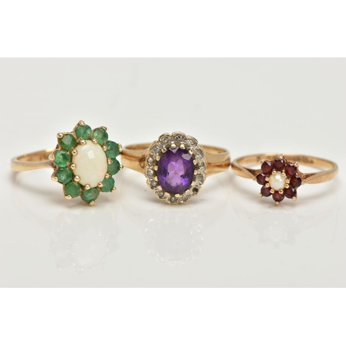 98 - THREE 9CT GOLD CLUSTER RINGS, the first an oval opal set with ten circular cut emeralds, set in yell... 