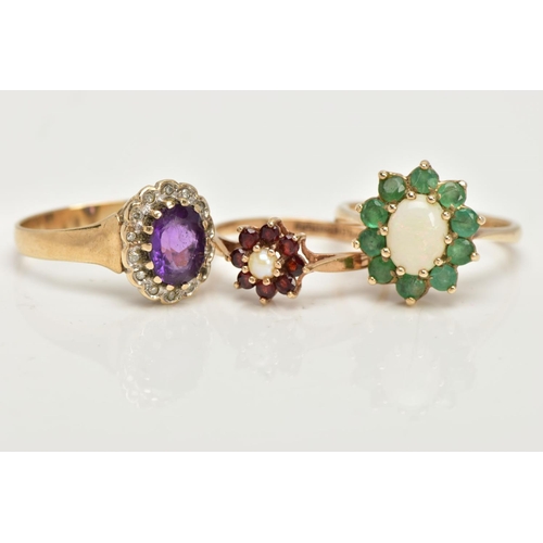 98 - THREE 9CT GOLD CLUSTER RINGS, the first an oval opal set with ten circular cut emeralds, set in yell... 