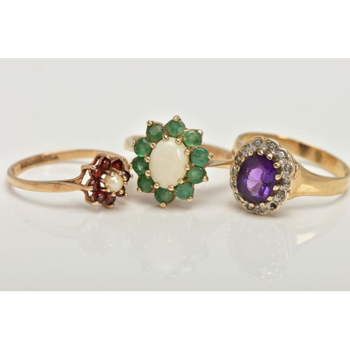 98 - THREE 9CT GOLD CLUSTER RINGS, the first an oval opal set with ten circular cut emeralds, set in yell... 