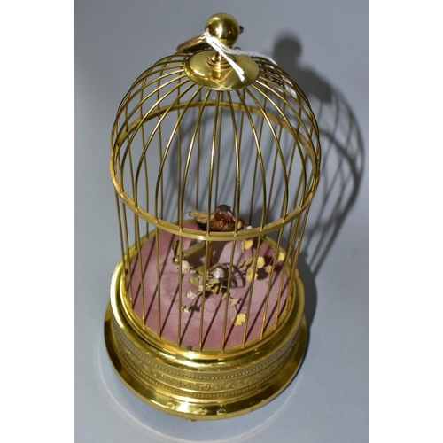 436 - A REPRODUCTION AUTOMATON SINGING BIRD IN A BRASS CAGE, fitted with a hanging loop, embossed decorati... 