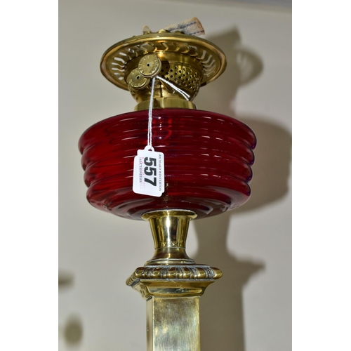 557 - THREE OIL LAMPS, two with glass reservoirs, the tallest measuring approximately 54cm having a square... 