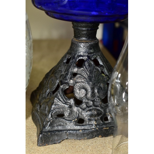 557 - THREE OIL LAMPS, two with glass reservoirs, the tallest measuring approximately 54cm having a square... 