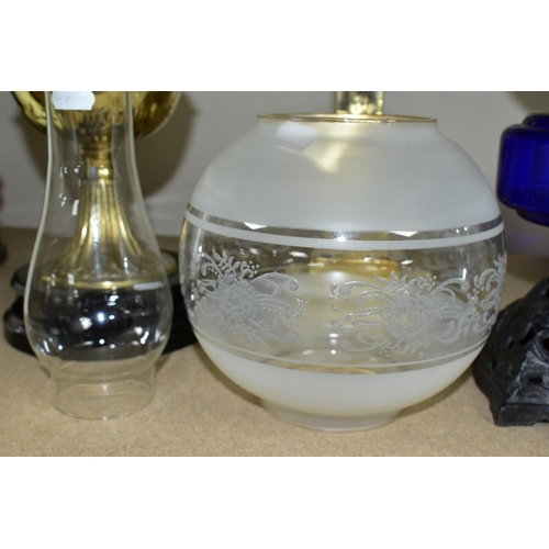 557 - THREE OIL LAMPS, two with glass reservoirs, the tallest measuring approximately 54cm having a square... 