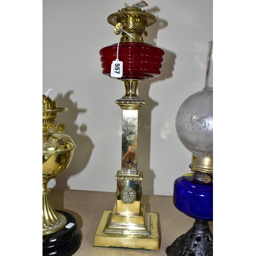 557 - THREE OIL LAMPS, two with glass reservoirs, the tallest measuring approximately 54cm having a square... 