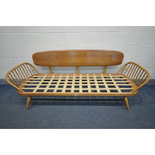 1435 - AN ERCOL MODEL 355 ELM AND BEECH STUDIO COUCH, with a surfboard back and spindled ends, with origina... 