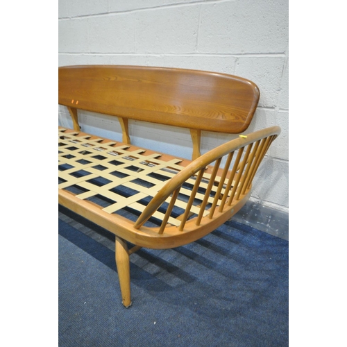 1435 - AN ERCOL MODEL 355 ELM AND BEECH STUDIO COUCH, with a surfboard back and spindled ends, with origina... 