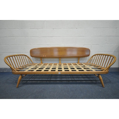 1435 - AN ERCOL MODEL 355 ELM AND BEECH STUDIO COUCH, with a surfboard back and spindled ends, with origina... 