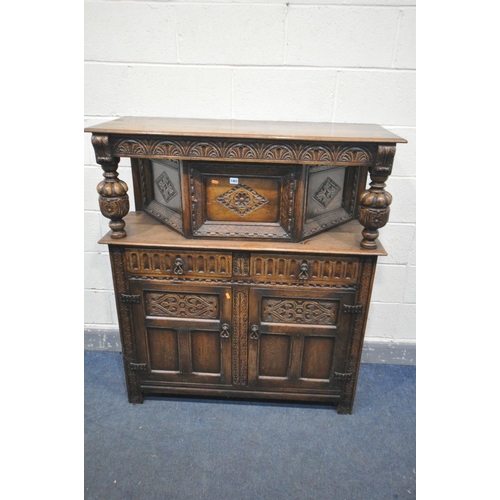 1463 - A REPRODUCTION CARVED OAK COURT CUPBOARD, the top with a single cupboard door, over two drawers and ... 