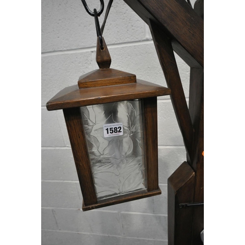 1582 - AN ARTS AND CRAFTS STYLE OAK STANDARD LAMP, with adjustable height clasp and a four sided glass lant... 