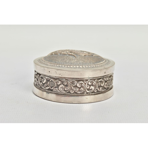 140 - AN INDIAN WHITE METAL BOX, the circular box with scroll and floral embossed detail and fitted lid, a... 