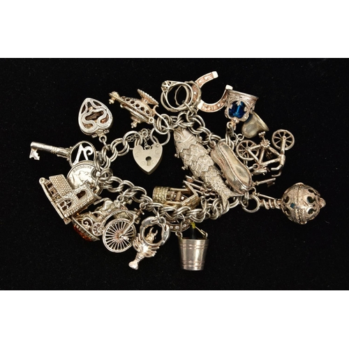 153 - A WHITE METAL CHARM BRACELET, comprising approximately twenty plus various charms to include a fish,... 