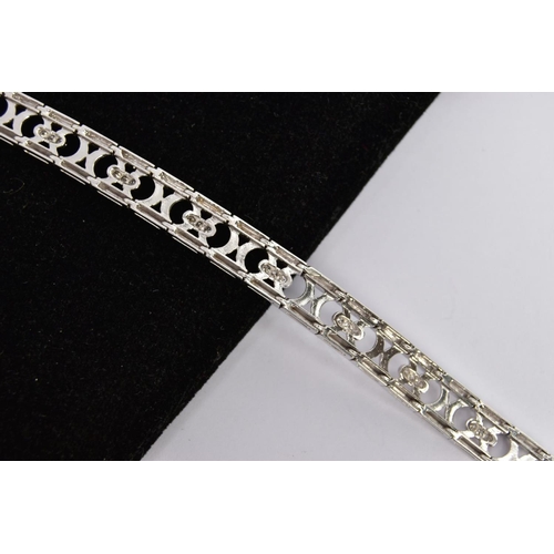 156 - A WHITE METAL DIAMOND OPENWORK BRACELET, with a trilogy of brilliant-cut diamonds each interspaced b... 