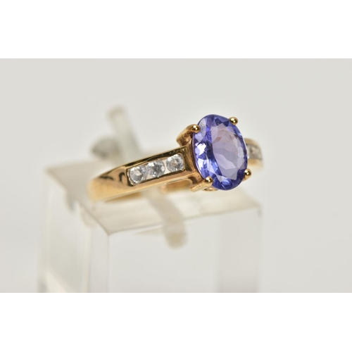 167 - A 9CT GOLD TANZANITE AND COLOURLESS GEM DRESS RING, the oval tanzanite, to the circular colourless g... 