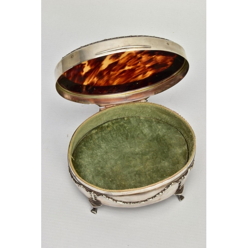 183 - AN EARLY 20TH CENTURY SILVER AND TORTOISESHELL HINGED BOX, the oval trinket box with embossed garlan... 