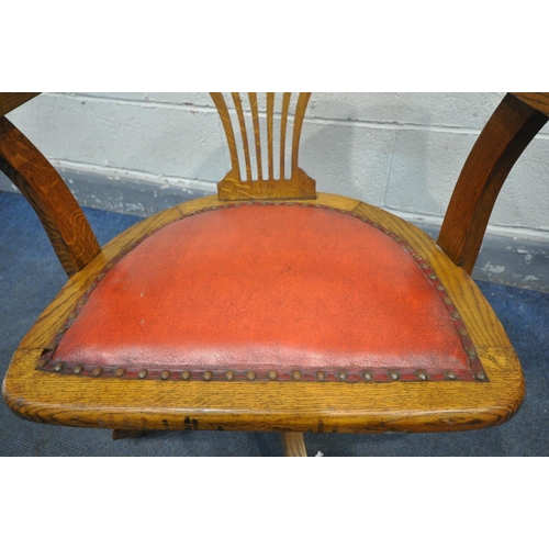 1414 - AN EARLY 2OTH CENTURY OAK SWIVEL OFFICE CHAIR, with red leather upholstered seat, on four legs, labe... 